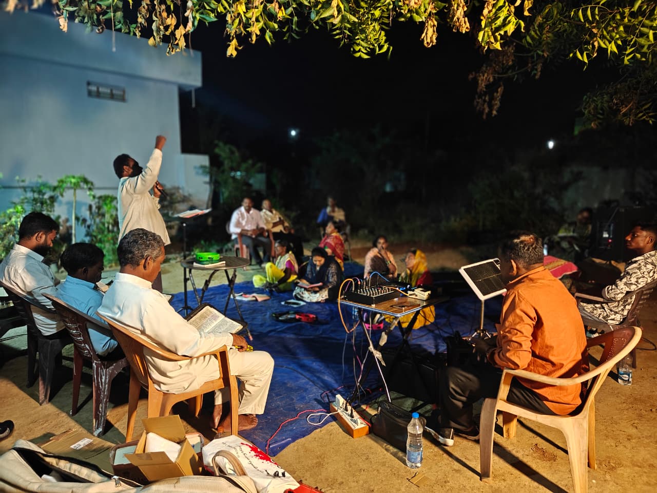 Night worship meeting with church members gathered outdoors.