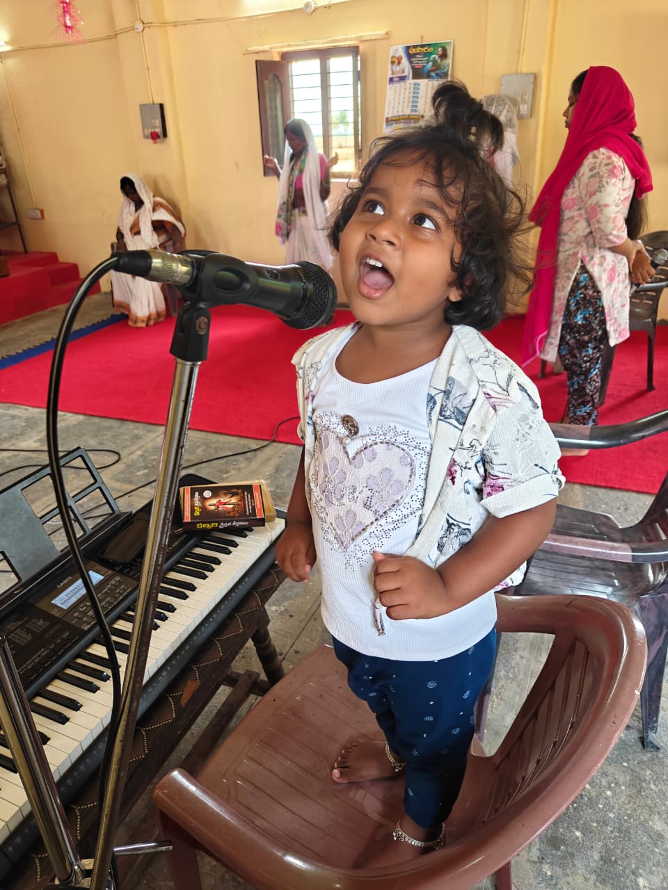 Child standing near worship instruments during Sunday school gathering.